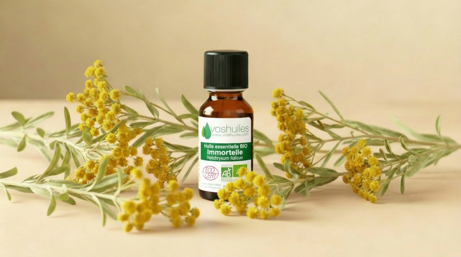 Flacon d’huile essentielle bio d'Immortelle, entouré de fleurs.